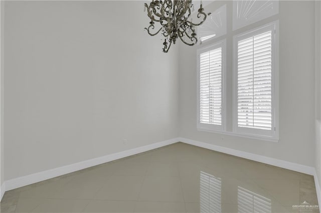 tiled spare room featuring a chandelier