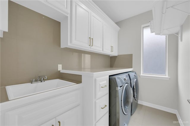 washroom with light tile patterned flooring, independent washer and dryer, sink, and cabinets