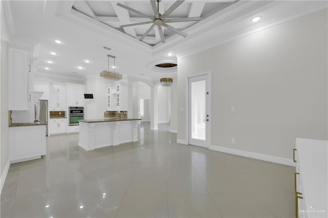 kitchen with hanging light fixtures, stainless steel appliances, white cabinets, a kitchen island, and ornamental molding