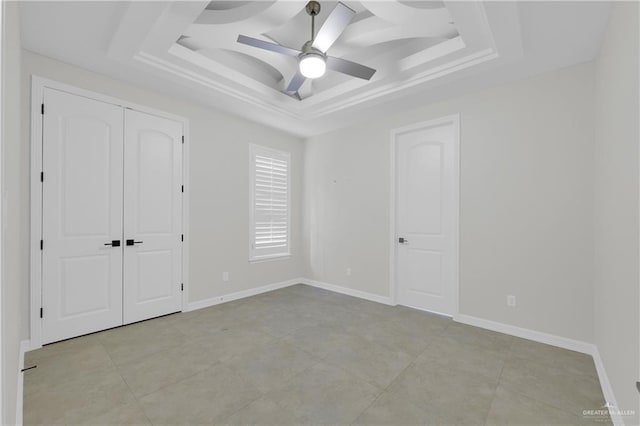 unfurnished bedroom featuring a tray ceiling, ceiling fan, and a closet