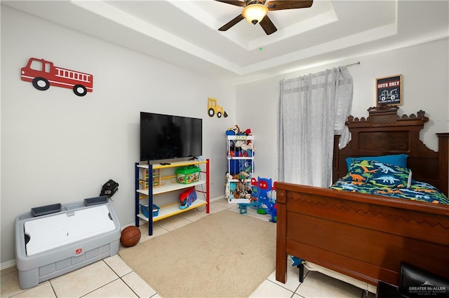 tiled bedroom with a tray ceiling and ceiling fan