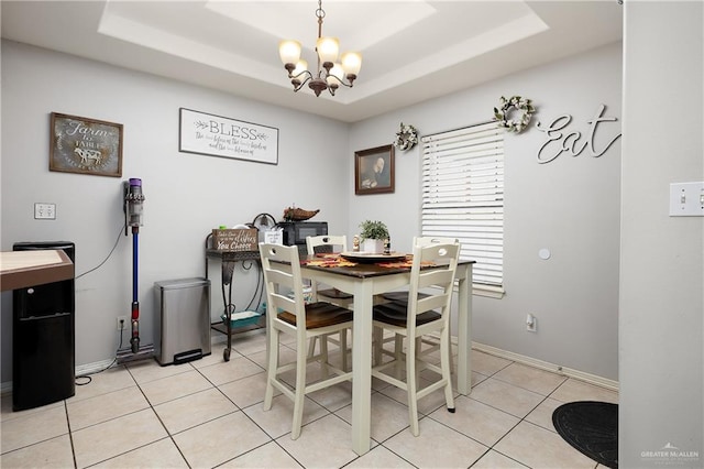 tiled dining space featuring a raised ceiling and an inviting chandelier