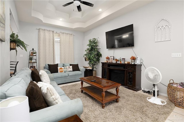 tiled living room featuring ceiling fan and a raised ceiling