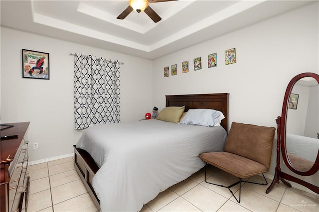 bedroom featuring ceiling fan, a raised ceiling, and light tile patterned floors