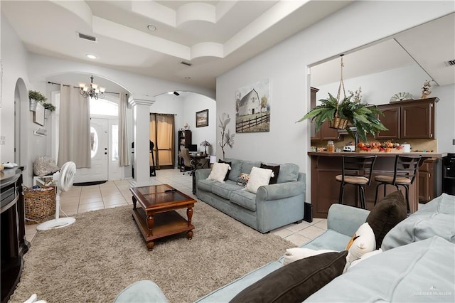 tiled living room with decorative columns and an inviting chandelier