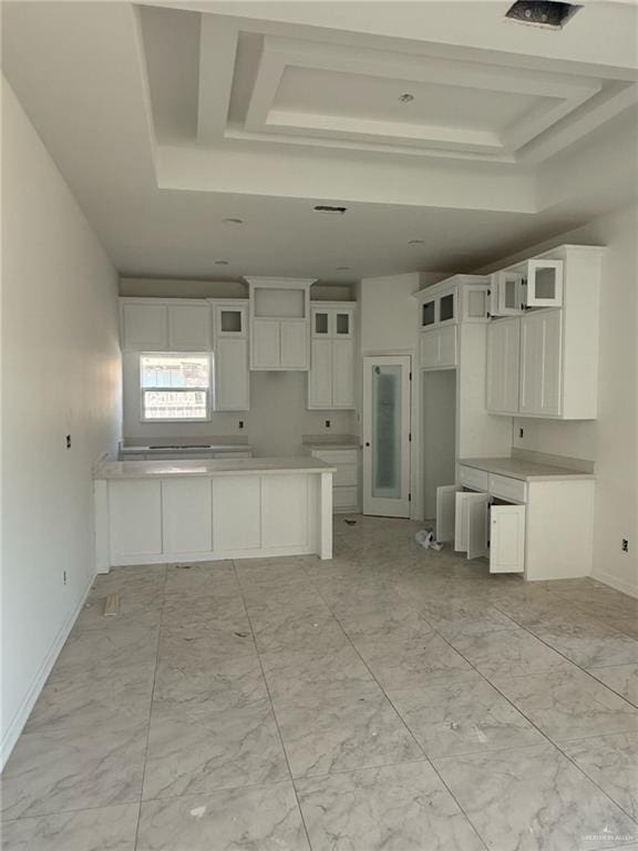 kitchen featuring white cabinetry, a tray ceiling, glass insert cabinets, and marble finish floor