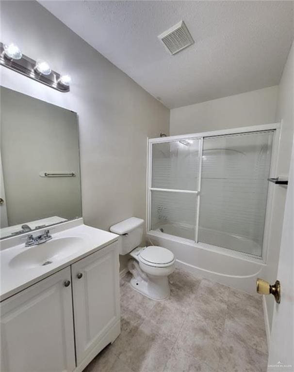 full bathroom with bath / shower combo with glass door, toilet, vanity, and a textured ceiling