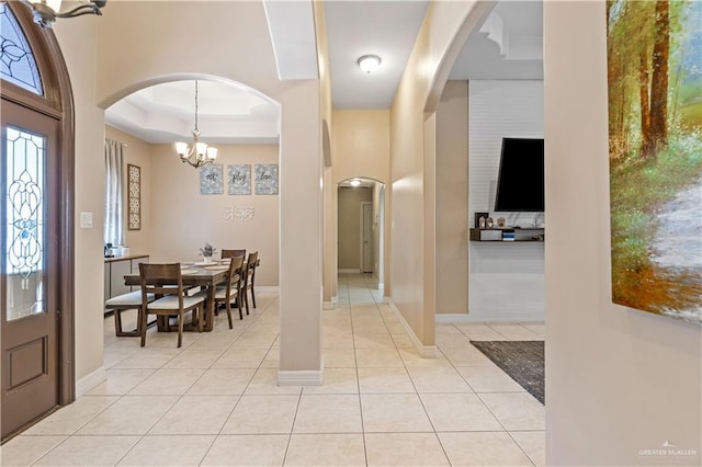 612 Persimmon Ave, Edinburg, TX 78539 - foyer with a tray ceiling, a chandelier, light tile patterned flooring, and arched walkways