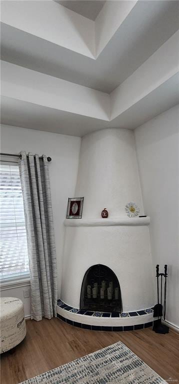 living room with a raised ceiling, hardwood / wood-style floors, and a fireplace