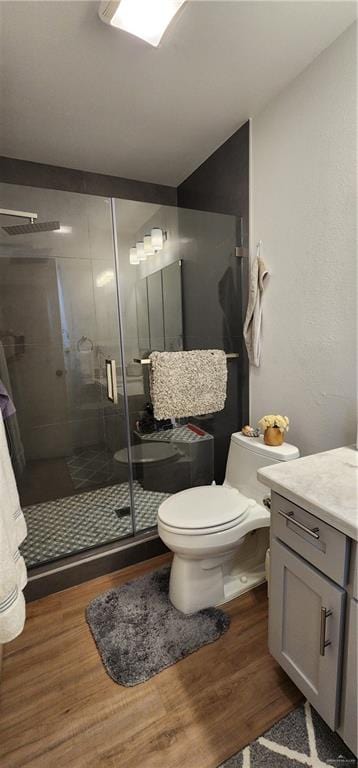 bathroom with an enclosed shower, wood-type flooring, vanity, and toilet