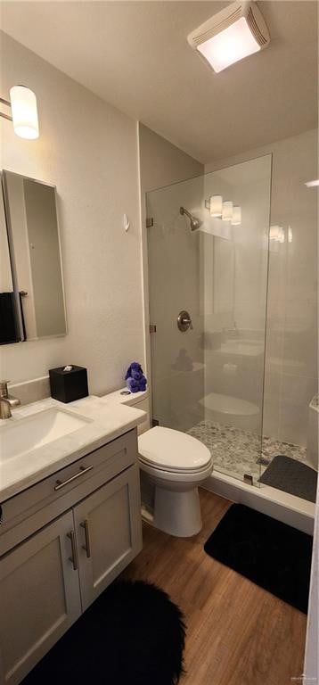 bathroom with vanity, tiled shower, hardwood / wood-style floors, and toilet