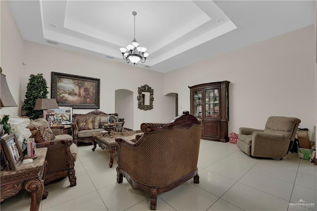 tiled living room featuring a raised ceiling and a notable chandelier