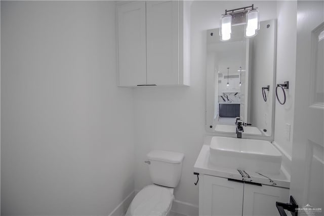 bathroom with baseboards, toilet, and vanity