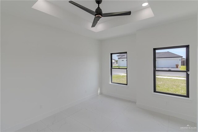 unfurnished room with plenty of natural light, baseboards, and a raised ceiling