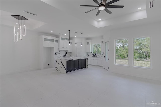 unfurnished living room with baseboards, visible vents, recessed lighting, ceiling fan, and a raised ceiling