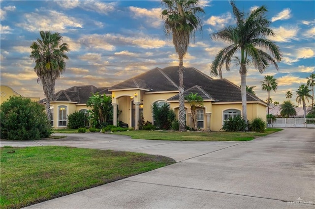 view of front of property featuring driveway, a front lawn, and stucco siding