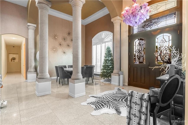 entrance foyer with a towering ceiling, ornate columns, baseboards, and arched walkways