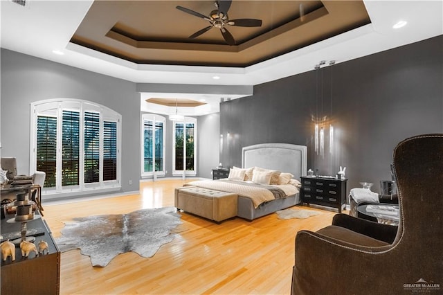 bedroom with visible vents, a tray ceiling, and wood finished floors