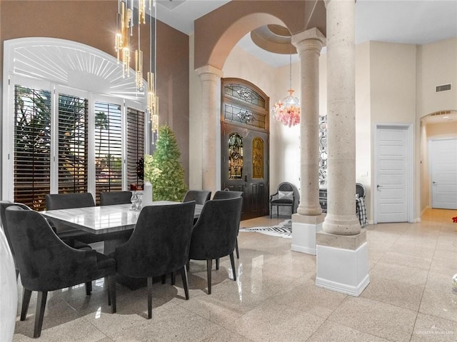 dining area featuring granite finish floor, visible vents, baseboards, a towering ceiling, and ornate columns