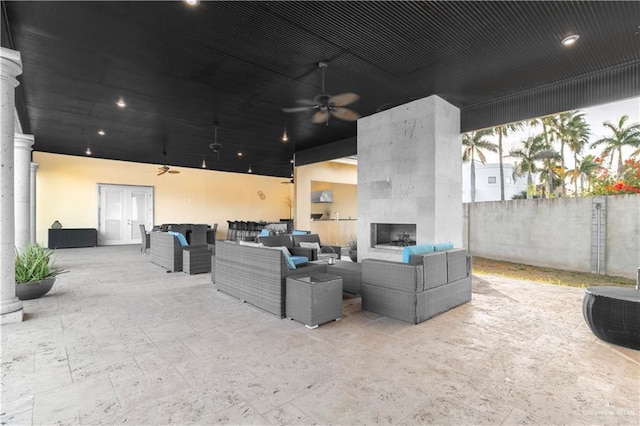 view of patio featuring an outdoor living space with a fireplace, fence, and a ceiling fan