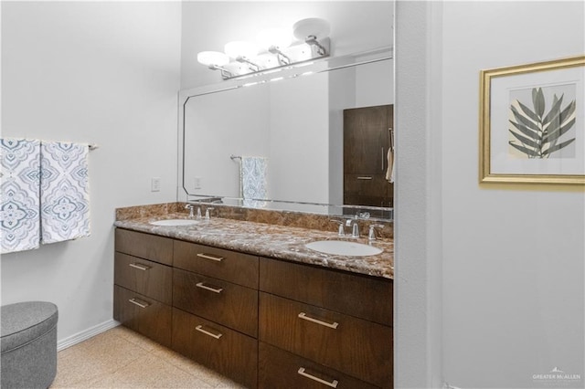 full bath with double vanity, a sink, and baseboards