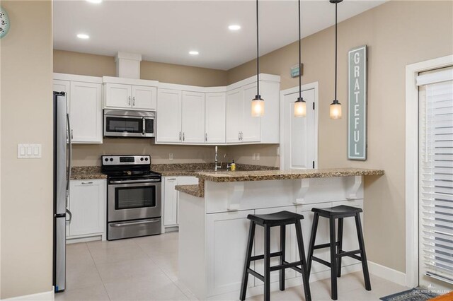 2803 Thompson St, Mission, TX 78573 - kitchen featuring stainless steel appliances, a breakfast bar area, dark stone counters, white cabinets, and recessed lighting