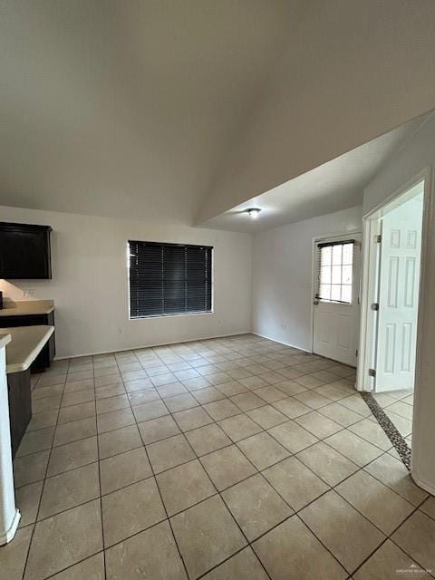 unfurnished room featuring light tile patterned floors and lofted ceiling
