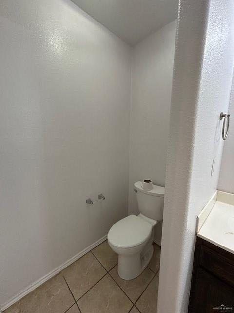 bathroom featuring toilet, baseboards, tile patterned flooring, and vanity