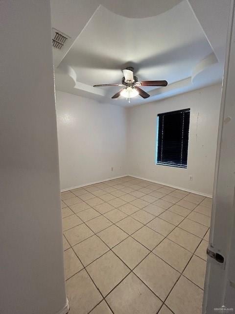 spare room with ceiling fan, a tray ceiling, light tile patterned flooring, and visible vents