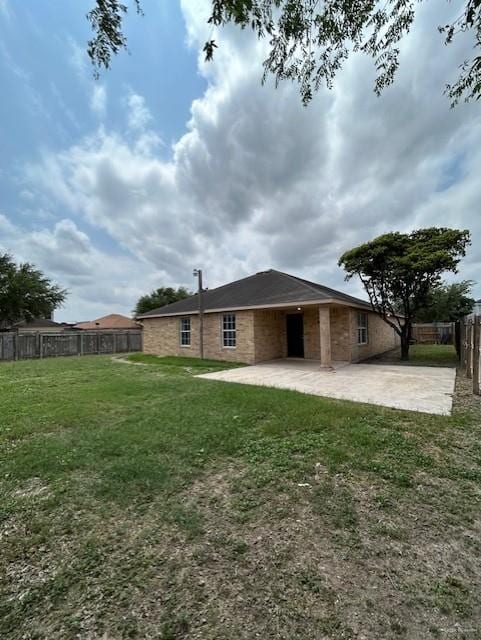 rear view of property with a fenced backyard, a yard, and a patio area