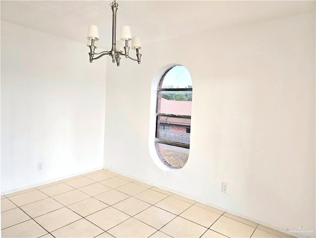 tiled empty room with a notable chandelier