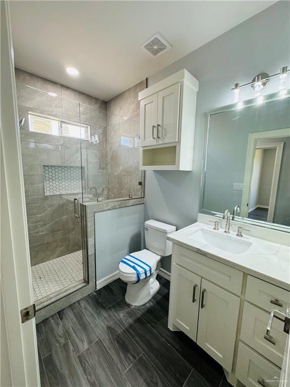 bathroom featuring vanity, a shower with shower door, and toilet