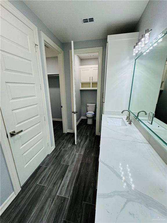 bathroom with toilet, vanity, and hardwood / wood-style flooring