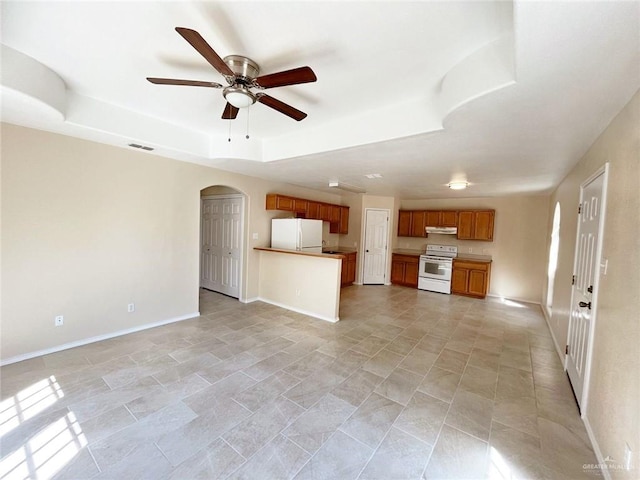 unfurnished living room featuring a raised ceiling and ceiling fan