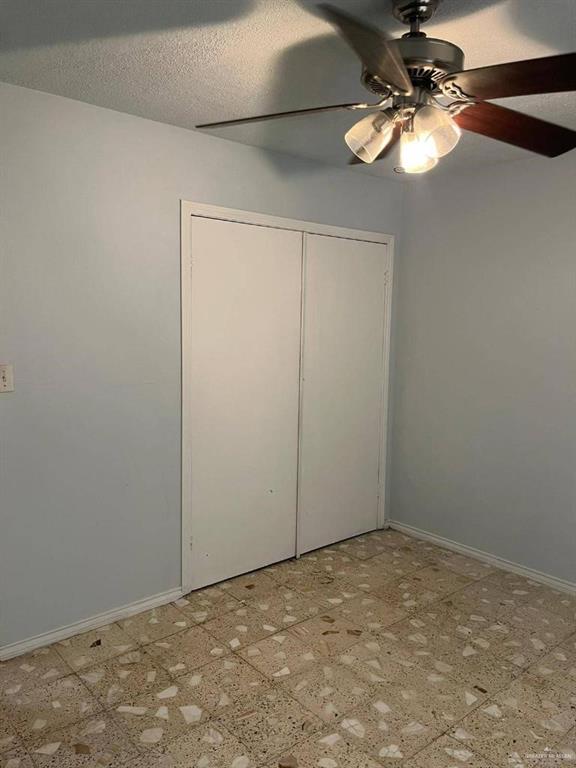 unfurnished bedroom with ceiling fan, a closet, and a textured ceiling