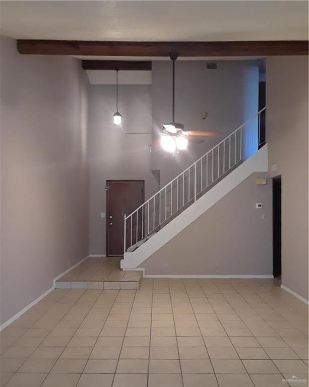 staircase featuring ceiling fan, beamed ceiling, tile patterned floors, and a towering ceiling