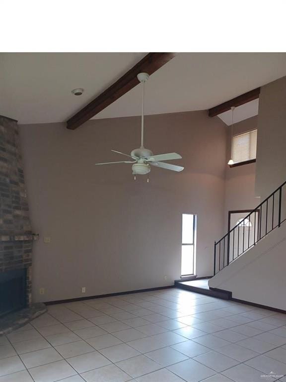 unfurnished living room featuring a brick fireplace, ceiling fan, light tile patterned floors, and beamed ceiling