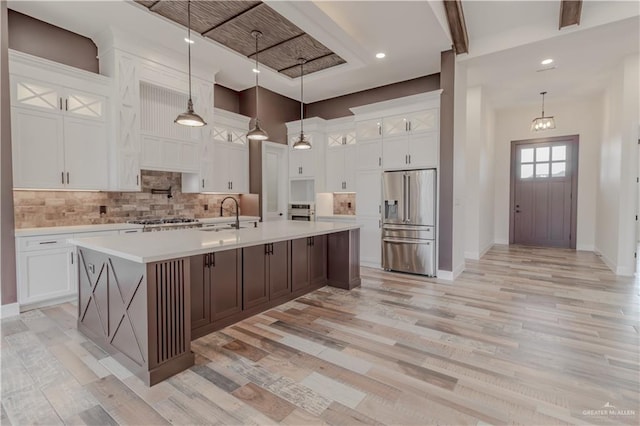 kitchen featuring a sink, light countertops, stainless steel appliances, light wood-type flooring, and backsplash