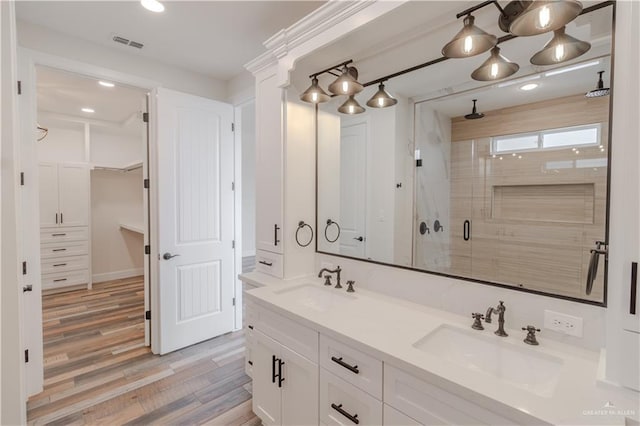 bathroom featuring visible vents, a sink, wood finished floors, and a shower stall