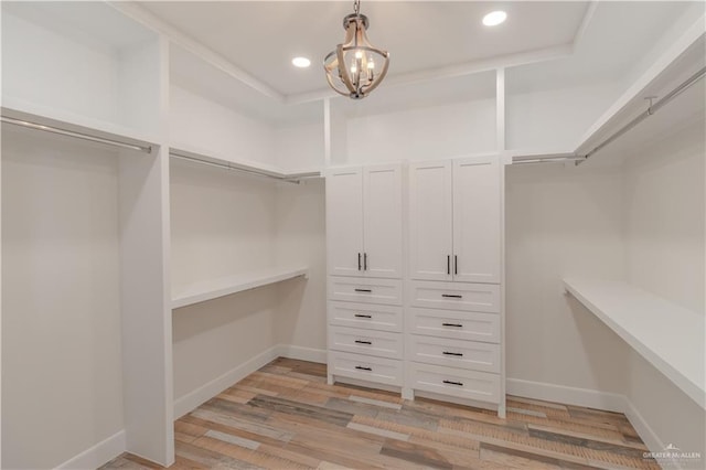 walk in closet with an inviting chandelier and light wood finished floors