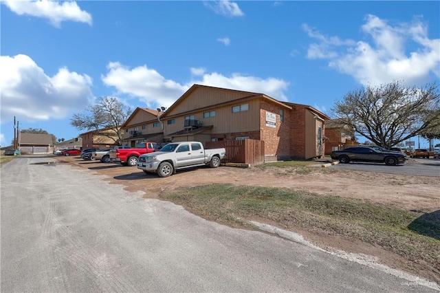 exterior space with uncovered parking and brick siding