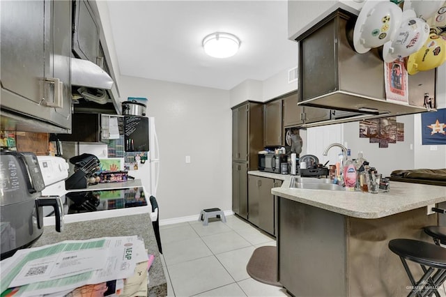 kitchen with light tile patterned floors, a sink, visible vents, light countertops, and a kitchen bar