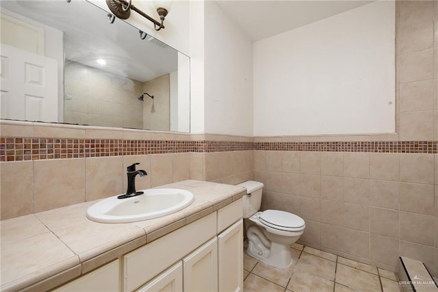 bathroom with tile patterned flooring, a baseboard heating unit, vanity, tile walls, and toilet