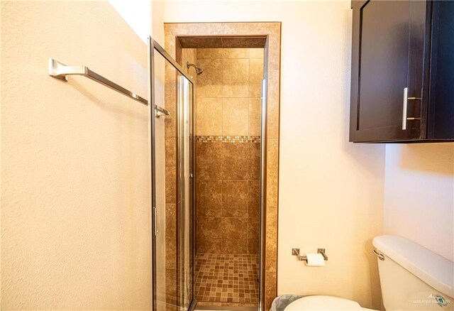 bathroom featuring toilet and a shower with shower door