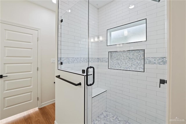 bathroom featuring wood finished floors, a shower stall, and baseboards