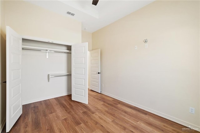 unfurnished bedroom featuring a closet, visible vents, baseboards, and wood finished floors