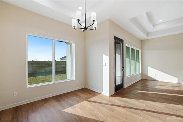 spare room featuring wood finished floors, a raised ceiling, and baseboards