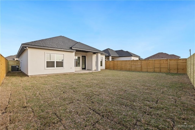 rear view of property with stucco siding, a fenced backyard, and a yard