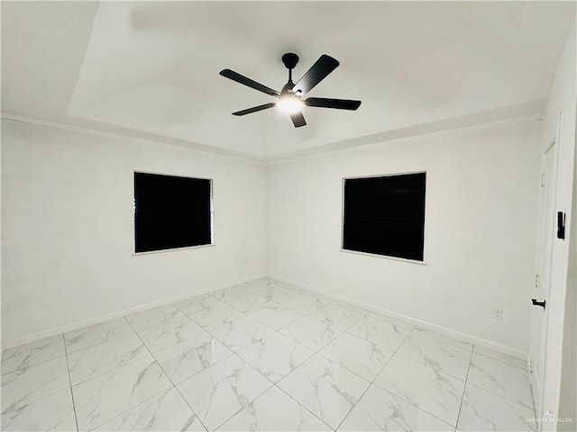 empty room featuring ceiling fan and a raised ceiling