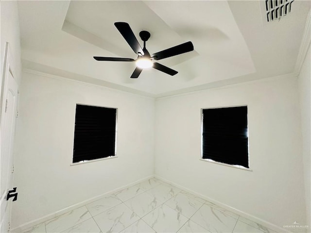 spare room featuring ornamental molding, ceiling fan, and a raised ceiling